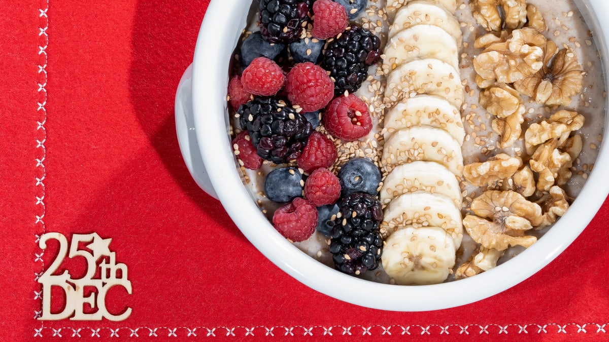 Delicious breakfast bowl with fresh fruits and nuts on a red holiday setting.